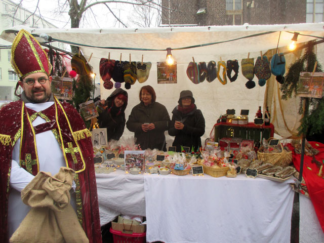 Der Weihnachtsmarktstand mit dem Standpersonal und dem Nikolaus
